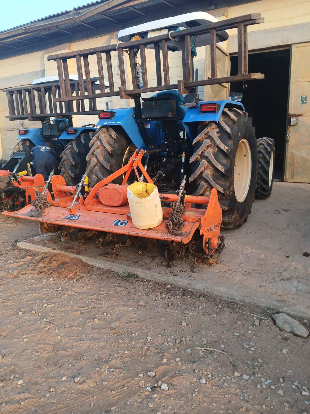 A rotavator implement attached to a Siroi Group tractor at the equipment yard.